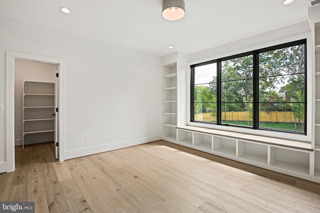 empty room with built in features and light hardwood / wood-style flooring