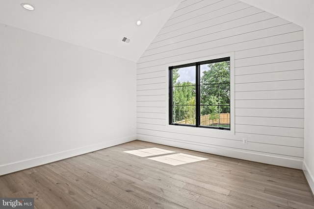 spare room featuring hardwood / wood-style floors, high vaulted ceiling, and wood walls