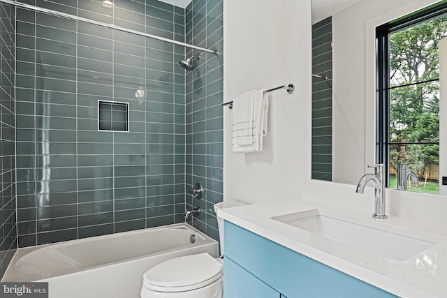 full bathroom featuring tiled shower / bath, vanity, and toilet