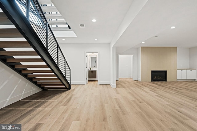 unfurnished living room with a fireplace and light wood-type flooring