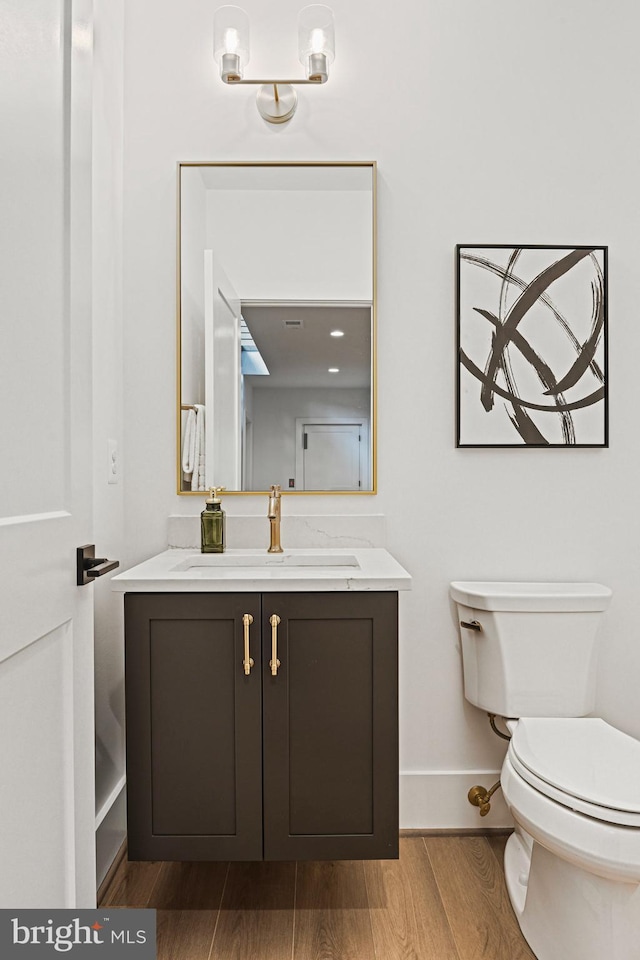 bathroom featuring vanity, hardwood / wood-style flooring, and toilet