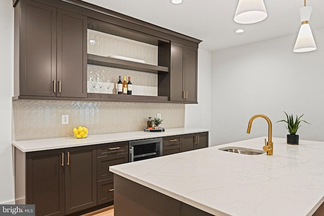 kitchen featuring sink, dark brown cabinets, tasteful backsplash, decorative light fixtures, and beverage cooler