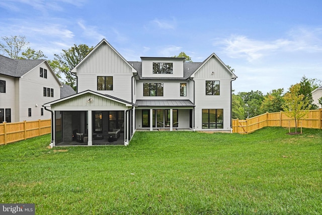 back of house with a sunroom and a lawn