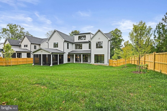 rear view of house featuring a sunroom and a lawn