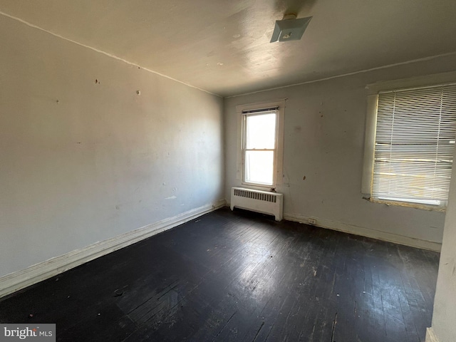 spare room featuring radiator and dark wood-type flooring