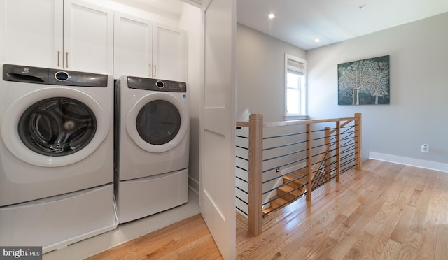 washroom featuring light hardwood / wood-style flooring, cabinets, and washer and dryer