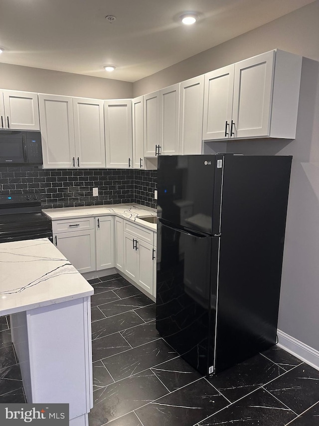 kitchen with dark tile floors, white cabinetry, tasteful backsplash, and black appliances