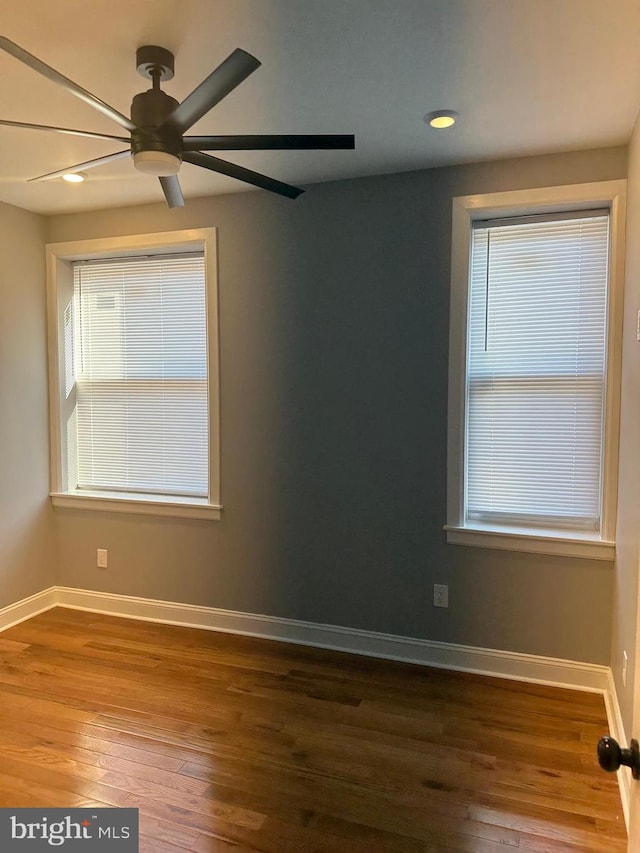 unfurnished room featuring dark hardwood / wood-style floors, ceiling fan, and a wealth of natural light