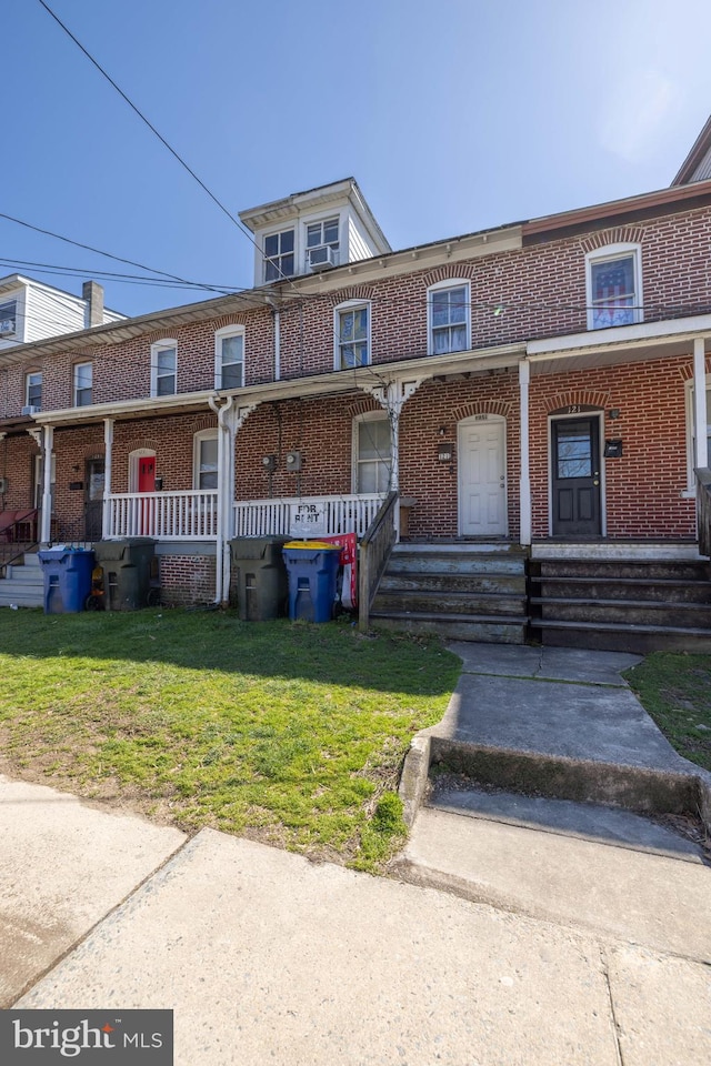 multi unit property featuring a front lawn and covered porch