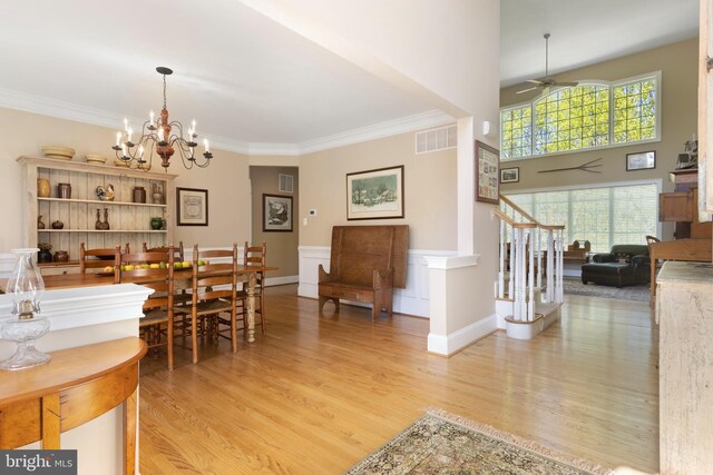 dining area featuring crown molding, ceiling fan with notable chandelier, light hardwood / wood-style flooring, and a high ceiling