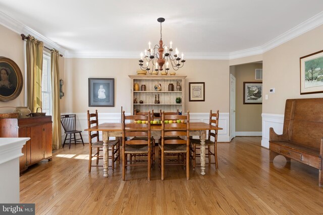 dining space featuring an inviting chandelier, crown molding, and light hardwood / wood-style flooring