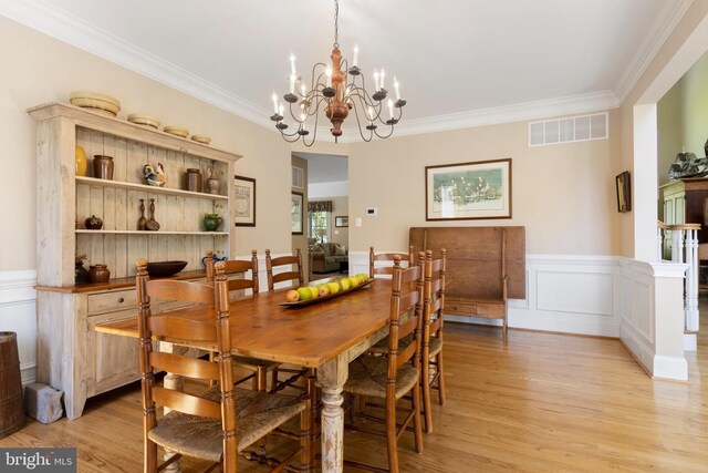 dining space featuring a notable chandelier, ornamental molding, and light wood-type flooring