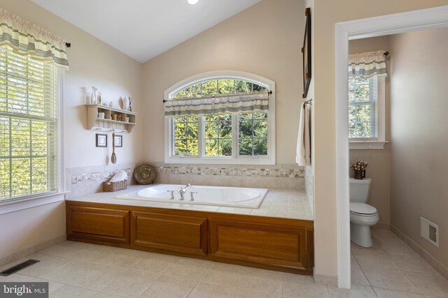 bathroom featuring vaulted ceiling, a bath, tile patterned floors, and toilet