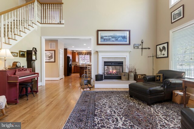 living room with a high ceiling, a multi sided fireplace, plenty of natural light, and light hardwood / wood-style flooring