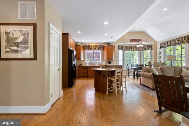 kitchen with light wood-type flooring, a breakfast bar area, a center island, and black fridge