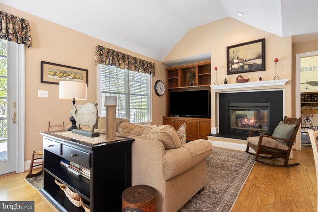 living room featuring lofted ceiling and light hardwood / wood-style floors