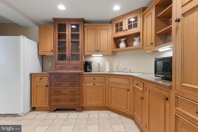 kitchen with light tile patterned flooring, white fridge, and sink