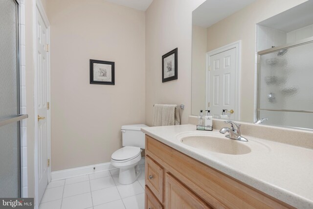 bathroom with vanity, a shower with door, tile patterned floors, and toilet