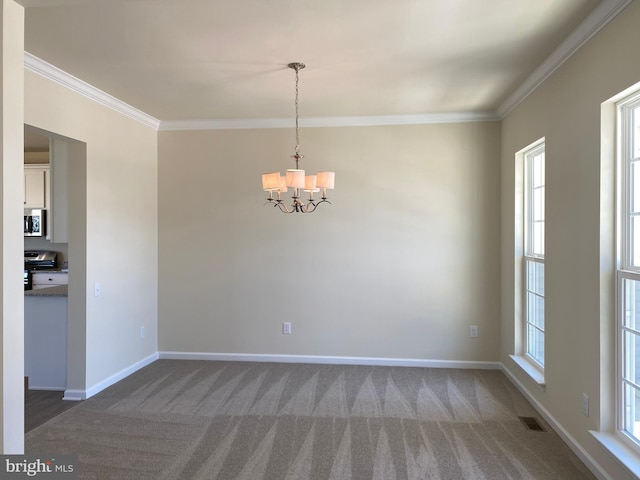 carpeted empty room featuring ornamental molding and a chandelier