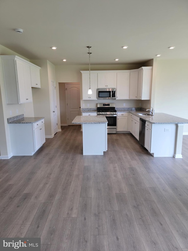 kitchen featuring light stone counters, hanging light fixtures, white cabinets, and appliances with stainless steel finishes