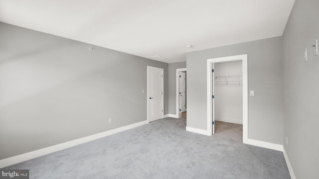 unfurnished bedroom featuring a closet, light carpet, and a spacious closet