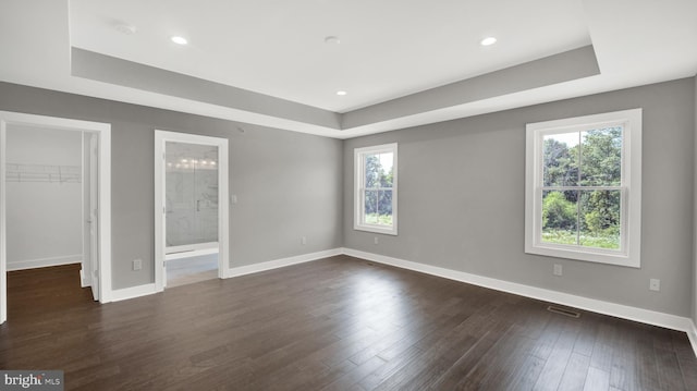 unfurnished room with dark wood-type flooring, a wealth of natural light, and a tray ceiling
