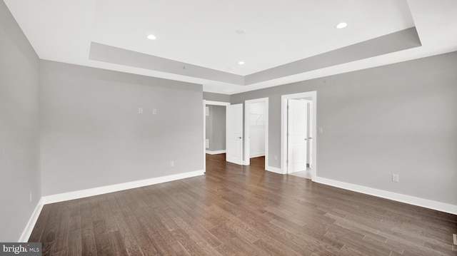 spare room featuring a tray ceiling and dark hardwood / wood-style flooring