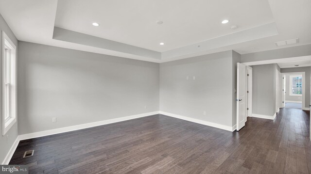 spare room featuring dark hardwood / wood-style floors and a tray ceiling