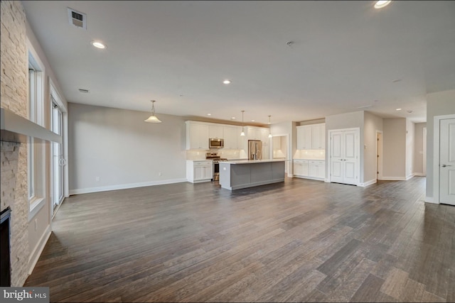 unfurnished living room featuring a stone fireplace and dark hardwood / wood-style floors