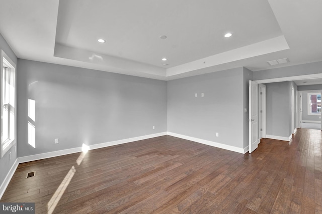 unfurnished room with a raised ceiling and dark wood-type flooring