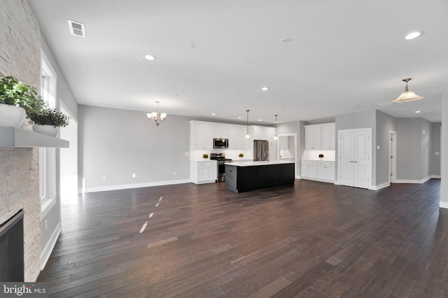 unfurnished living room with a chandelier, a stone fireplace, and dark hardwood / wood-style floors