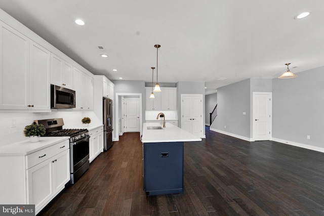 kitchen featuring dark hardwood / wood-style flooring, appliances with stainless steel finishes, white cabinets, sink, and hanging light fixtures