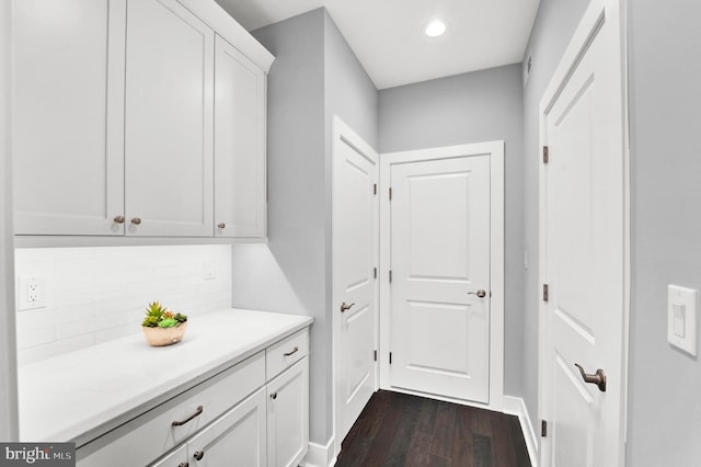 interior space featuring dark hardwood / wood-style flooring, backsplash, and white cabinets