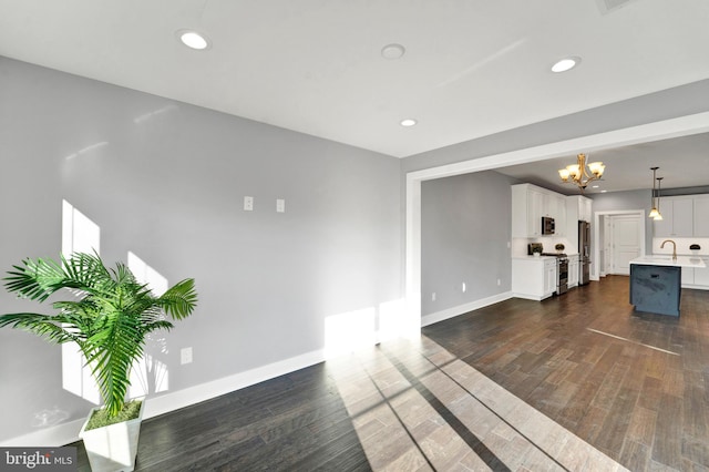 unfurnished living room with an inviting chandelier, dark hardwood / wood-style floors, and sink