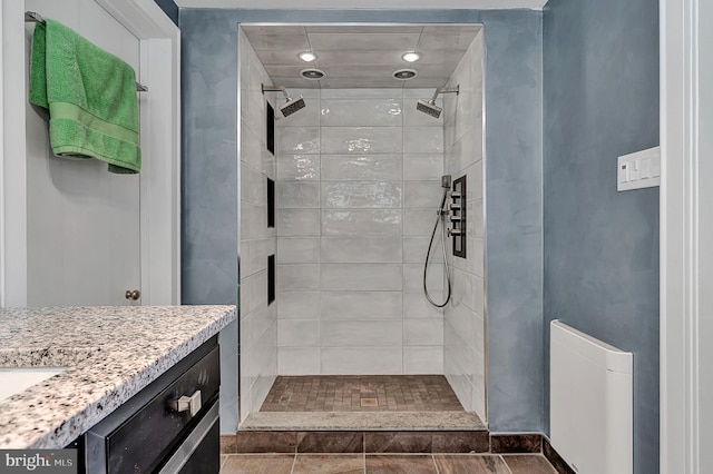 bathroom featuring tile floors, tiled shower, and vanity