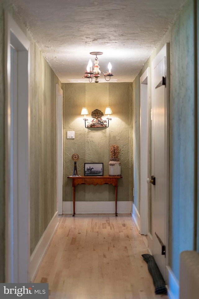 corridor with an inviting chandelier and light wood-type flooring