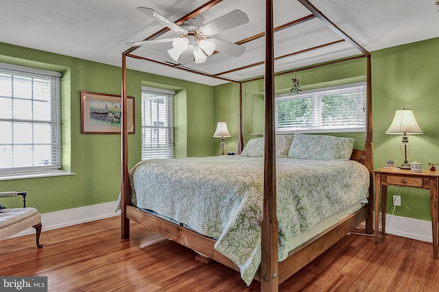 bedroom featuring ceiling fan, multiple windows, and hardwood / wood-style flooring