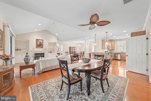 dining area featuring built in shelves, ceiling fan, light hardwood / wood-style flooring, and vaulted ceiling