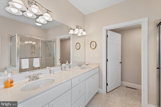 bathroom with a shower with door, vanity, and tile patterned flooring