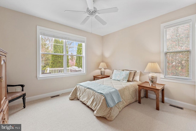 bedroom with multiple windows, ceiling fan, and light carpet