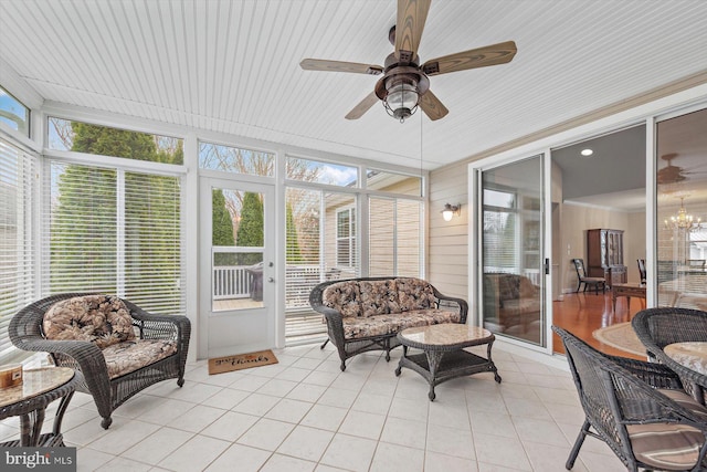 sunroom featuring ceiling fan with notable chandelier