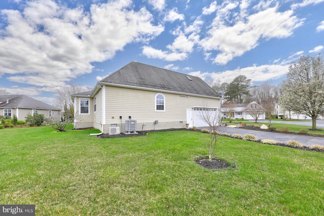 view of side of property with a garage, a yard, and central AC