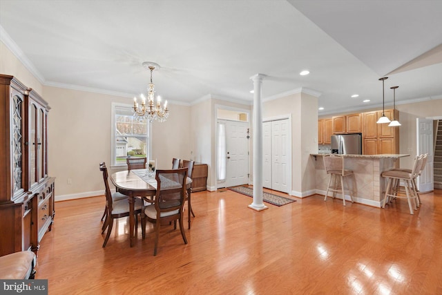 dining area with light wood-type flooring, an inviting chandelier, ornamental molding, and ornate columns