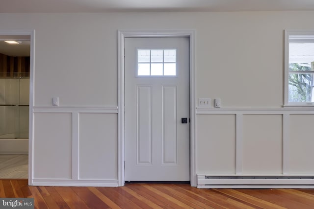 entrance foyer with baseboard heating, light wood-type flooring, and plenty of natural light