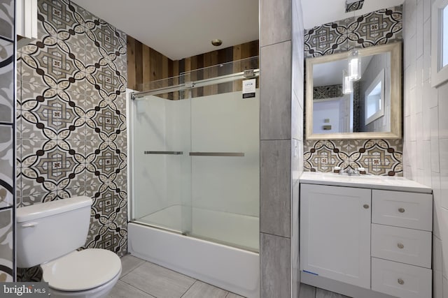 full bathroom with vanity, backsplash, tile flooring, bath / shower combo with glass door, and toilet