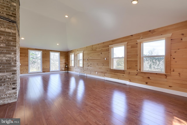 unfurnished room featuring brick wall, dark hardwood / wood-style flooring, and wooden walls