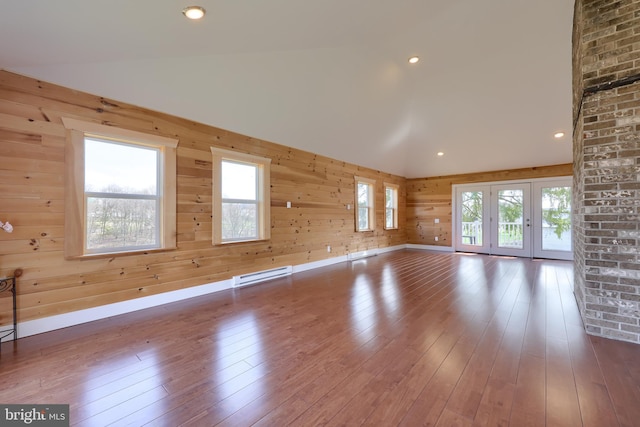 spare room featuring dark hardwood / wood-style flooring, wood walls, brick wall, a baseboard heating unit, and vaulted ceiling