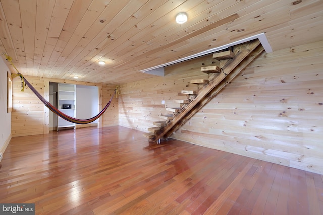 basement featuring wooden walls, light hardwood / wood-style floors, and wooden ceiling