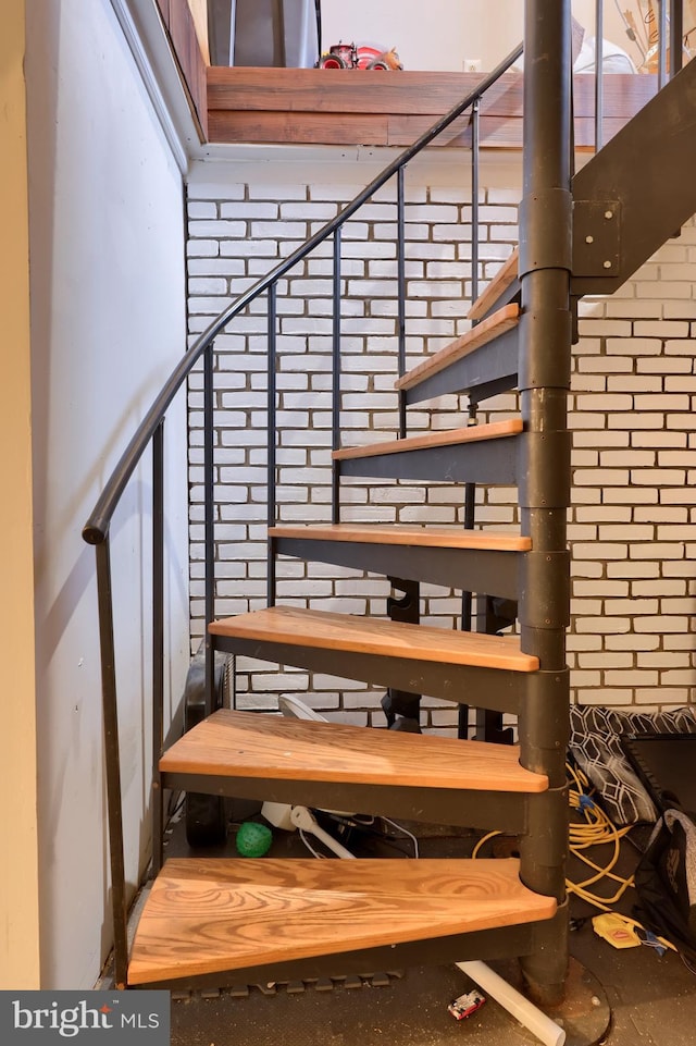 staircase featuring brick wall