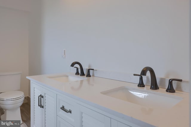 bathroom with toilet, hardwood / wood-style floors, and vanity